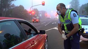 A police officer wears Personal Protective Equipment at a checkpoint in Auckland.