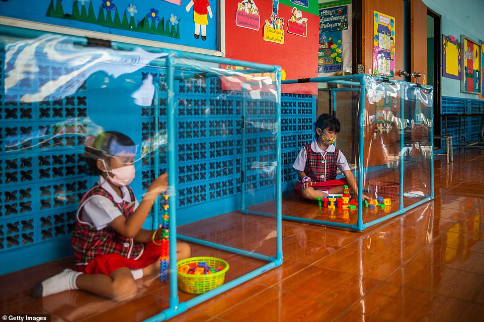Thai kindergardeners wear face masks as they play in screened in play areas used for social distancing at the Wat Khlong Toey School
